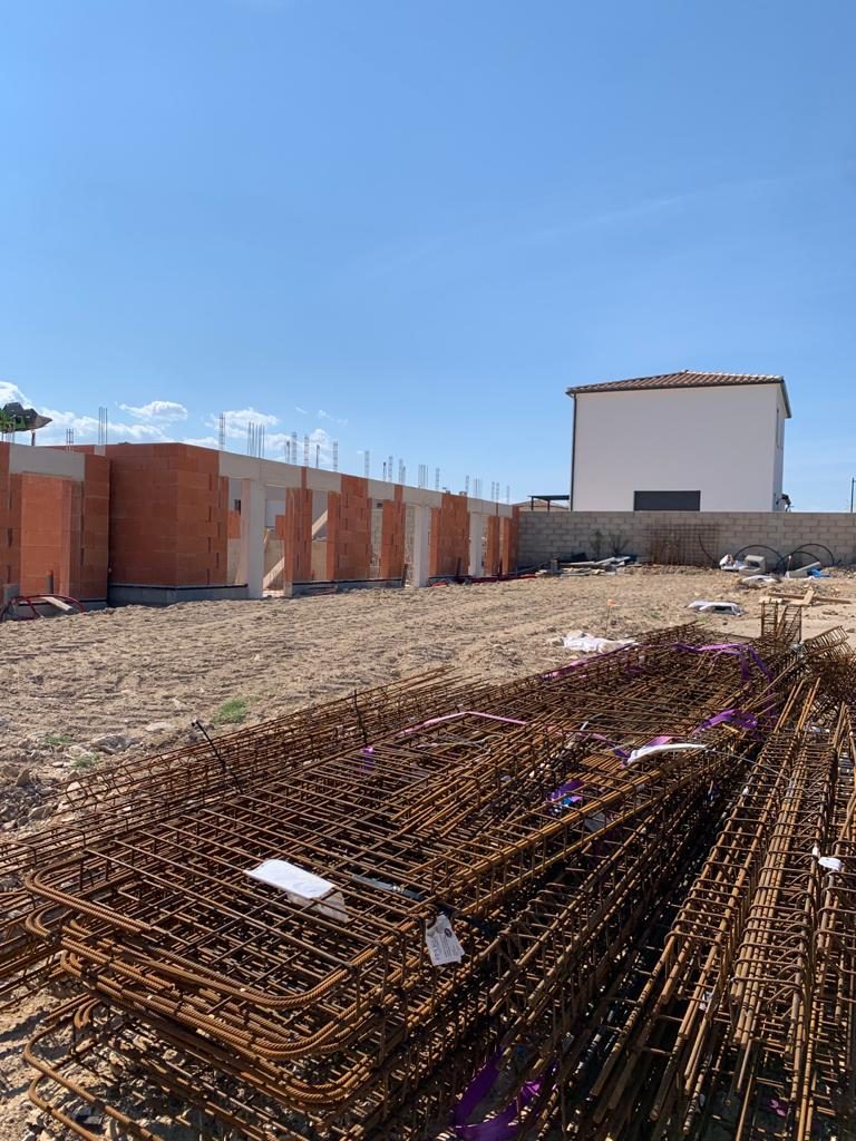 Murs en brique et poteaux béton d'un bâtiment collectif, armatures prêtes à poser au premier plan