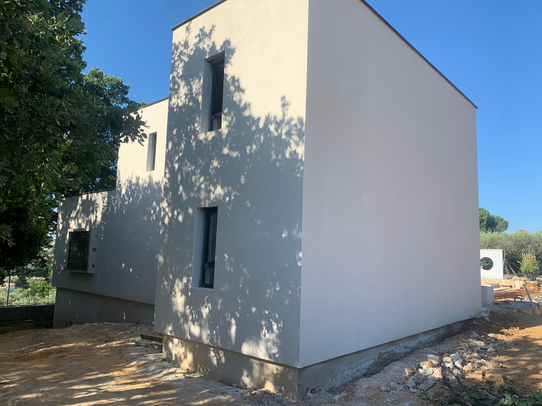 Villa contemporaine à toit-terrasse, façades enduites blanches sous le soleil du Gard